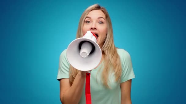 Blonde junge Frau kündigt per Lautsprecher vor blauem Hintergrund etwas an — Stockvideo