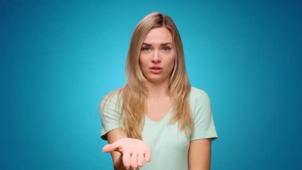 Mujer joven disgustada cubriendo los ojos y haciendo gestos se detienen contra fondo azul — Vídeos de Stock