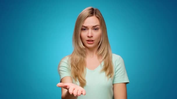 Displeased young woman covering eyes and gesturing stop against blue background — Stock Video