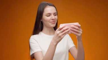 Stüdyoda akıllı telefonuyla oyun oynayan genç bir kadın.