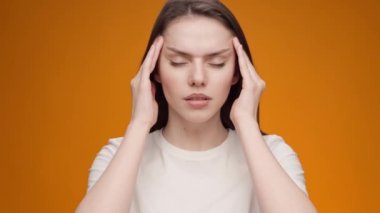 Sarı arka planda duran genç bayanın başı ağrıyor.