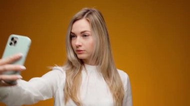 Stüdyoda akıllı telefonuyla selfie çeken genç bir kadın.