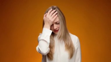 Üzgün bir kadın yüzüne tokat atıyor, çaresiz hissediyor.