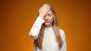 Üzgün bir kadın yüzüne tokat atıyor, çaresiz hissediyor.