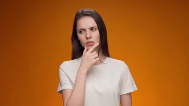 Sarışın kadın, parlak bir fikir üzerinde düşünüyor, sarı arka plana kafa yoruyor.