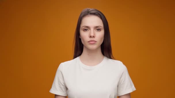 Jonge vrouw staan tegen gele achtergrond en kijken naar camera — Stockvideo