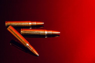 Siyah parlak arkaplanda kırmızı yansımalı tüfek mermileri ya da kartuşlar