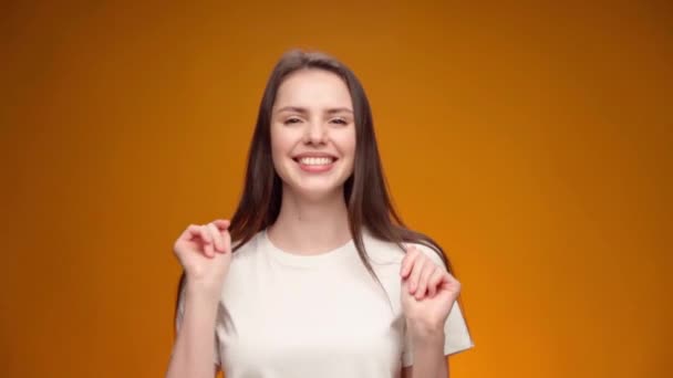 Šťastná mladá žena tančí s radostí na žlutém pozadí — Stock video