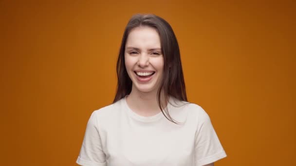 Genç bir kadın şakaya gülüyor ve baş parmağını kaldırıyor, sarı arka plan — Stok video