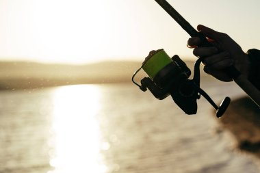 Balıkçı elleri oltayı yakından tutuyor.