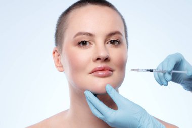 Kısa saçlı güzel bir kadın yüzüne güzellik iğnesi vuruluyor.