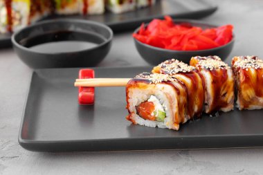 Siyah seramik tabakta yılan balıklı ejderha suşi rulosu.