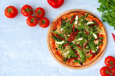 Bitkilerle taze pizza ve gri masada kurutulmuş domatesler.