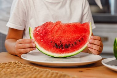 Tanımlanamayan küçük kız elinde olgun bir karpuz dilimi tutuyor