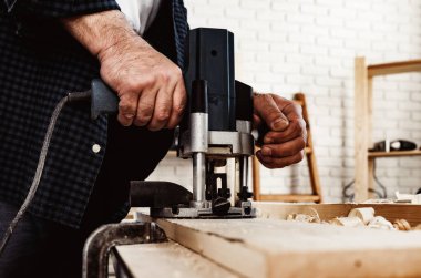 Marangoz elektrikli testereyle odun kesiyor.