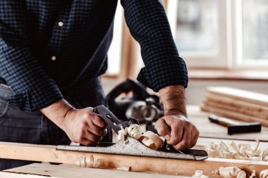 Marangozların elleri el uçağıyla bir tahta döşeme yapıyor.