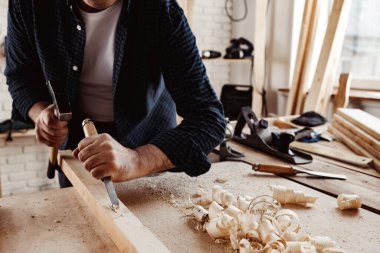 Bir marangozun elleri keski ve çekiçle çalışır.