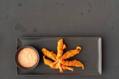 Siyah seramik tabakta soslu kızarmış karides.