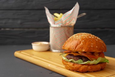 Lezzetli hamburger ve patates kızartması tahtada siyah arka planda