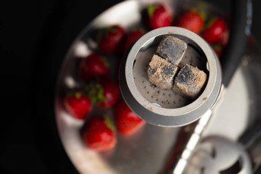 Çilek aromalı nargile koyu arkaplanı kapatır.