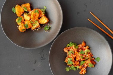 Fıstıklı kızarmış tavuk ve gri arka plandaki kaselerde kızarmış patlıcan.