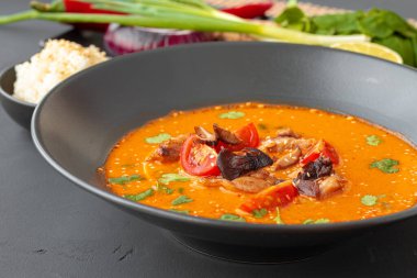 Tom Yam Thai çorbası gri masada siyah kasede