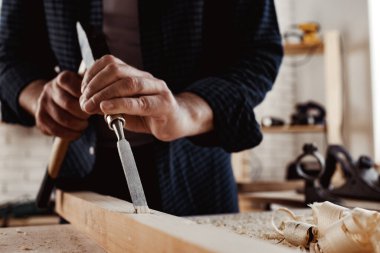 Bir marangozun elleri keski ve çekiçle çalışır.