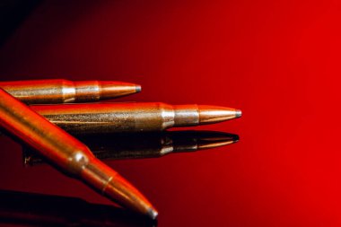 Siyah parlak arkaplanda kırmızı yansımalı tüfek mermileri ya da kartuşlar