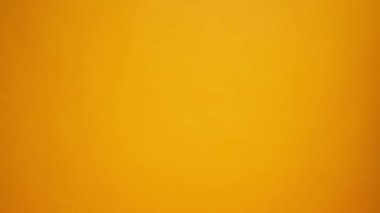 İnsanların elleri birbirlerinin yanından geçerken sarı stüdyo arka planında yiyecek paketleri taşıyorlar.