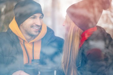 Genç çift bardağın arkasındaki kafede kahve içiyor.