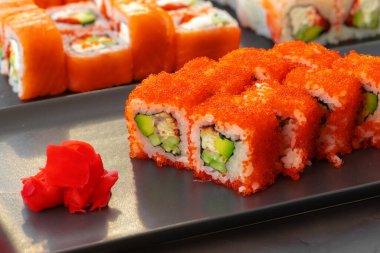 Gri arka planda servis edilen çeşitli suşi dürümleri.