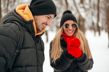 Mutlu çift dışarıda karlı parkta sarılıp gülümsüyor.