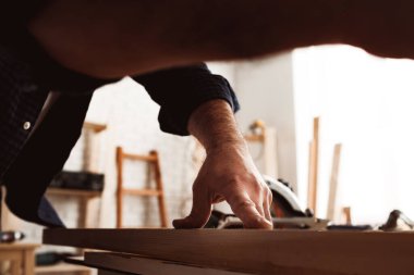 Erkek marangoz atölyede ahşap bir barda çalışıyor.