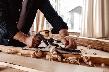 Marangozların elleri el uçağıyla bir tahta döşeme yapıyor.