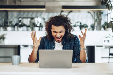 Dizüstü bilgisayarına bakan stresli ve hayal kırıklığına uğramış genç bir adam kötü haber aldı.