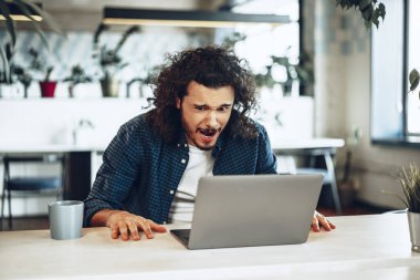 Dizüstü bilgisayarına bakan stresli ve hayal kırıklığına uğramış genç bir adam kötü haber aldı.