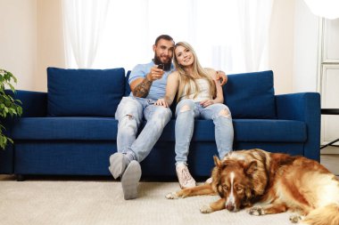 Genç ve sevgi dolu bir çift oturma odasında köpekleri ile dinleniyor.