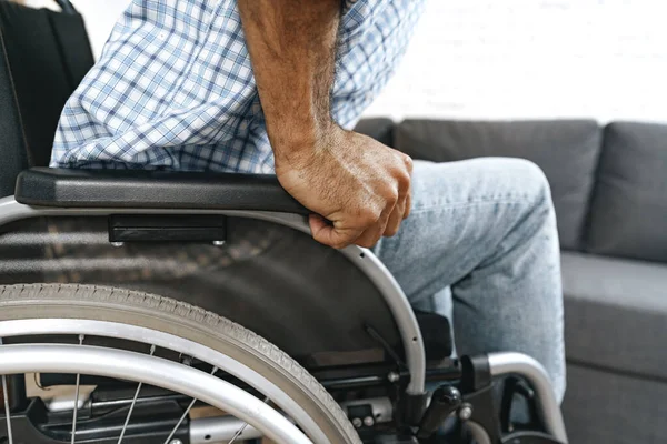 Siyah engelli adam evde tekerlekli sandalyeye oturur.