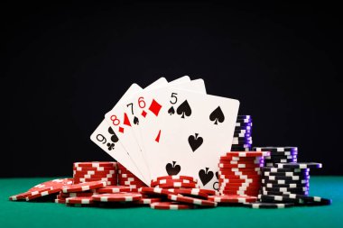 Poker çipleri ve siyah arkaplanda oyun kartları
