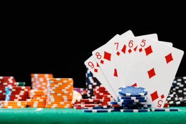 Poker çipleri ve siyah arkaplanda oyun kartları