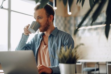 Ofiste bilgisayarla çalışan genç bir işadamı.