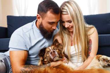 Genç ve sevgi dolu bir çift oturma odasında köpekleri ile dinleniyor.