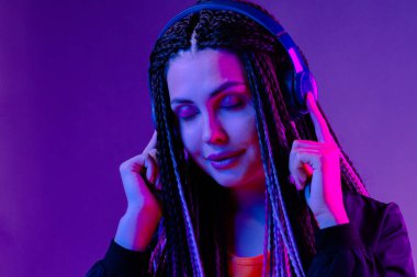 Uzun saçlı güzel bir kadın kulaklıkla müzik dinliyor.