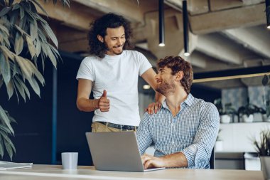 İki genç iş adamı modern ofiste bazı fikirleri tartışıyor.