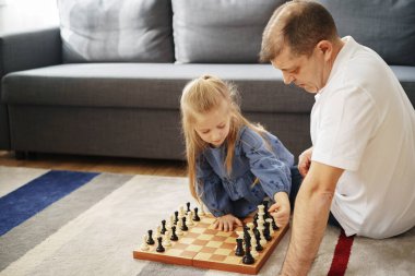 Büyükbaba ve torun evde satranç oynuyorlar.