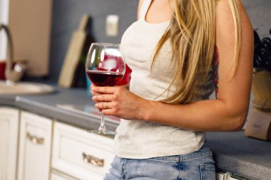 Mutfakta elinde bir bardak şarapla tanınmayan sarışın kadın.