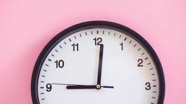 Black clock on pink background close up — Stock Video