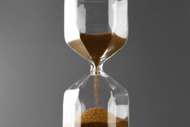 Gri zemin üzerinde kum olan kum saati. Yakın plan.