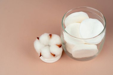 Kağıt arkaplanda bir kavanozda cilt bakımı için pamuk diskler