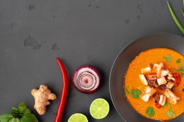 Tom yam Thai çorbası, gri arka planda servis edilir.